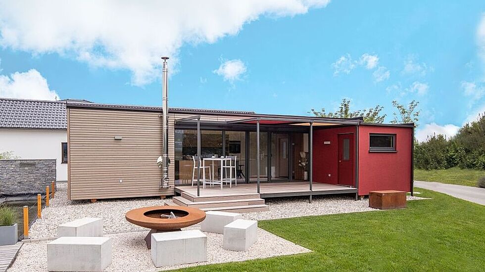 Hier sieht man das Tiny Haus von Genböck Haus mit einer Holzschalung und einer angebauten Sauna. 